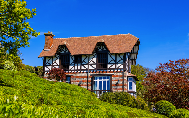 Fachwerkhaus mit Garten vor blauem Himmel.