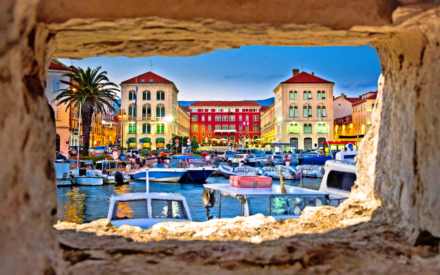 Blick auf Hafen mit Booten und historischen Gebäuden bei Abenddämmerung.
