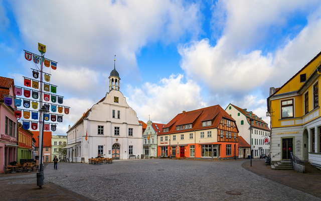 Historischer Marktplatz mit Rathaus und bunten Gebäuden.