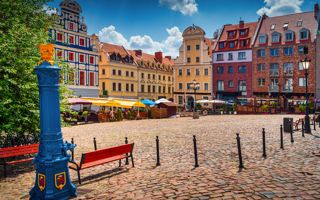 Alter Marktplatz mit historischen Gebäuden und einer blauen Wasserpumpe.