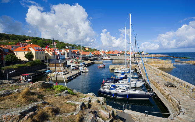 Hafen mit Segelbooten und bunten Gebäuden unter blauem Himmel.