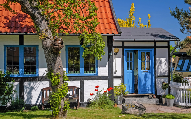 Fachwerkhaus mit blauem Türrahmen und Garten im Sommer.