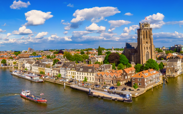 Stadtansicht am Wasser mit historischem Turm und blauen Himmel.
