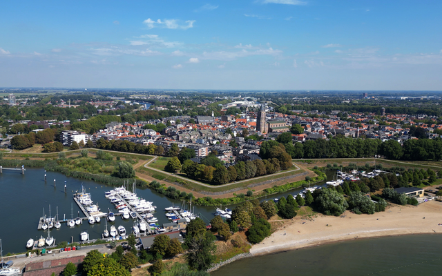Luftaufnahme eines Hafens mit Stadt im Hintergrund und Strand im Vordergrund.