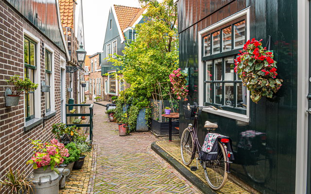 Fahrrad an der engen, von Blumen gesäumten Straße Kerkepad in Volendam, Niederlande.