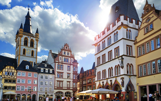 Historische Gebäude und Menschen auf einem Platz bei sonnigem Wetter.