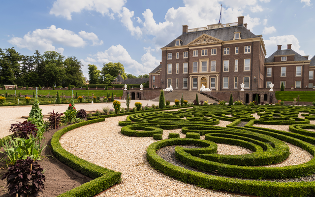Barockgarten mit Heckenlabyrinth vor einem großen Herrenhaus.