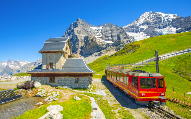 Rote Bergbahn vor einem Bergmassiv in einer alpinen Landschaft.