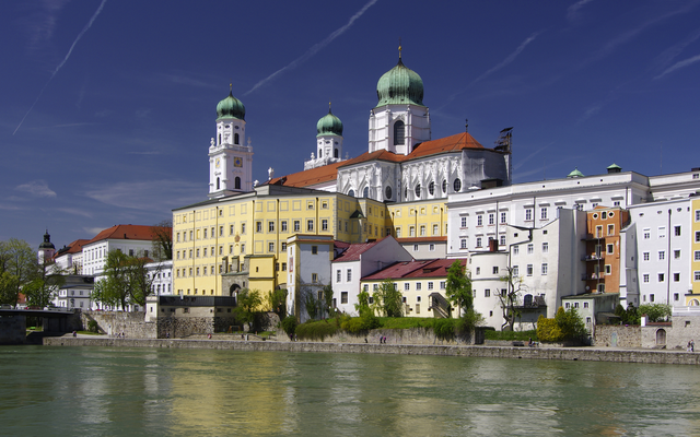 Stadtansicht von Passau am Fluss mit Dom und Gebäuden bei klarem Himmel.