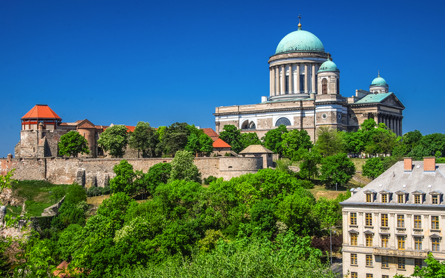 Basilika und alte Festung auf Hügel mit Bäumen und historischem Gebäude im Vordergrund