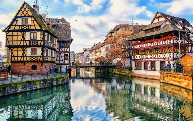 Fachwerkhäuser an einem Kanal in einer historischen Stadt bei sonnigem Wetter.