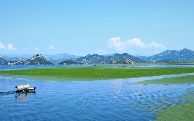 Boot auf einem See vor Bergpanorama unter blauem Himmel.
