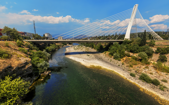 Moderne Brücke über einen Fluss in einer städtischen Landschaft.