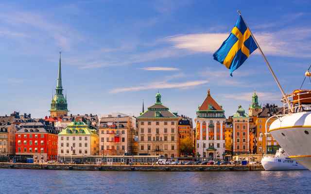 Blick auf Stockholm mit Gebäuden und schwedischer Flagge bei sonnigem Wetter.