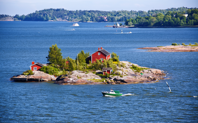 Kleine Insel mit rotem Haus im blauen Meer, Boot auf dem Wasser.