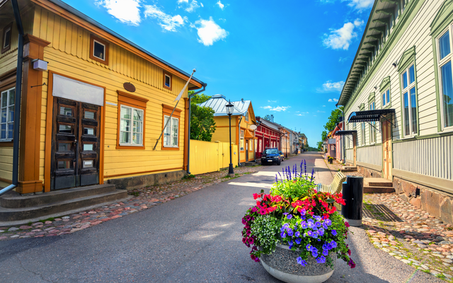 Historische Straße mit bunten Holzhäusern und Blumenschmuck im Vordergrund.