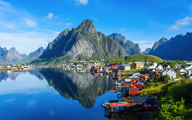 Fjordlandschaft mit Berg, Wasser und bunten Häusern.