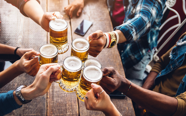 Mehrere Menschen stoßen mit Biergläsern an.