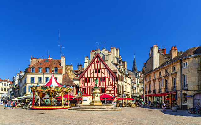 Historischer Platz mit Fachwerkhaus, Karussell und blauem Himmel.