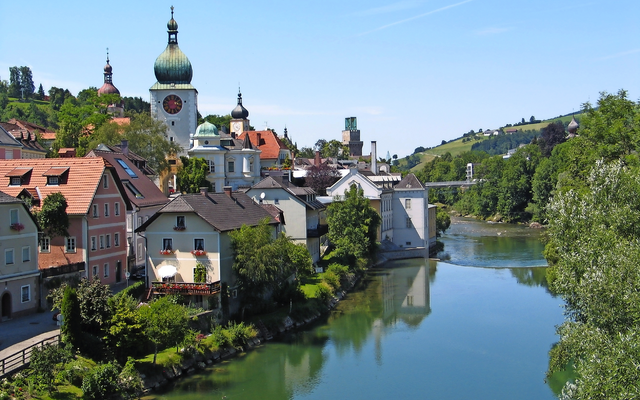 Malerische Kleinstadt mit Fluss und Kirchturm bei klarem Wetter.