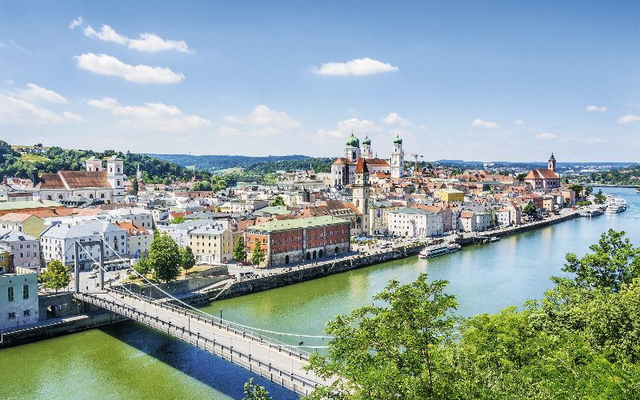 Blick auf Passau mit der Donau und einer Brücke im Vordergrund bei sonnigem Wetter.