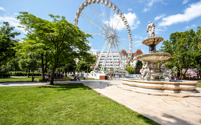 Riesenrad und Brunnen in einem Park bei sonnigem Wetter
