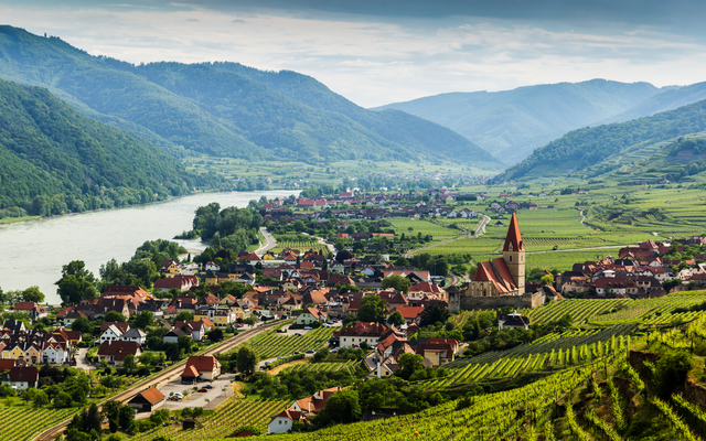 Idyllische Landschaft mit Fluss, Dorf und Weinbergen in einem Tal.