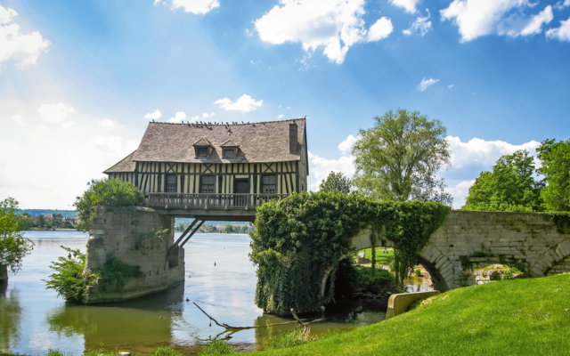 Fachwerkhaus auf einer alten Brücke über einem Fluss an einem sonnigen Tag.