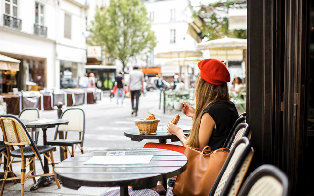 Junge Frau isst ein Croissant in einem Pariser Café.