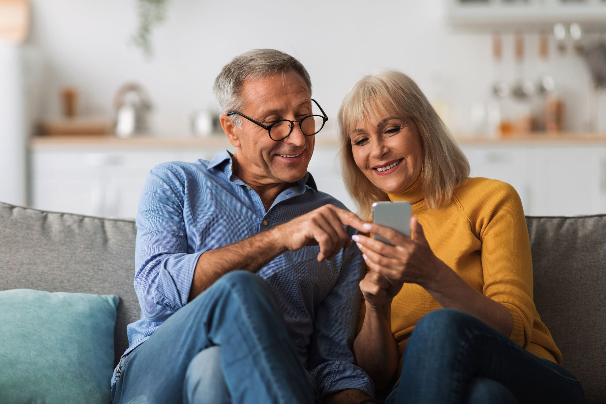 © Prostock-studio - stock.adobe.com Ältere Ehepartner, die zu Hause auf dem Sofa sitzen und ihr Handy benutzen WEB